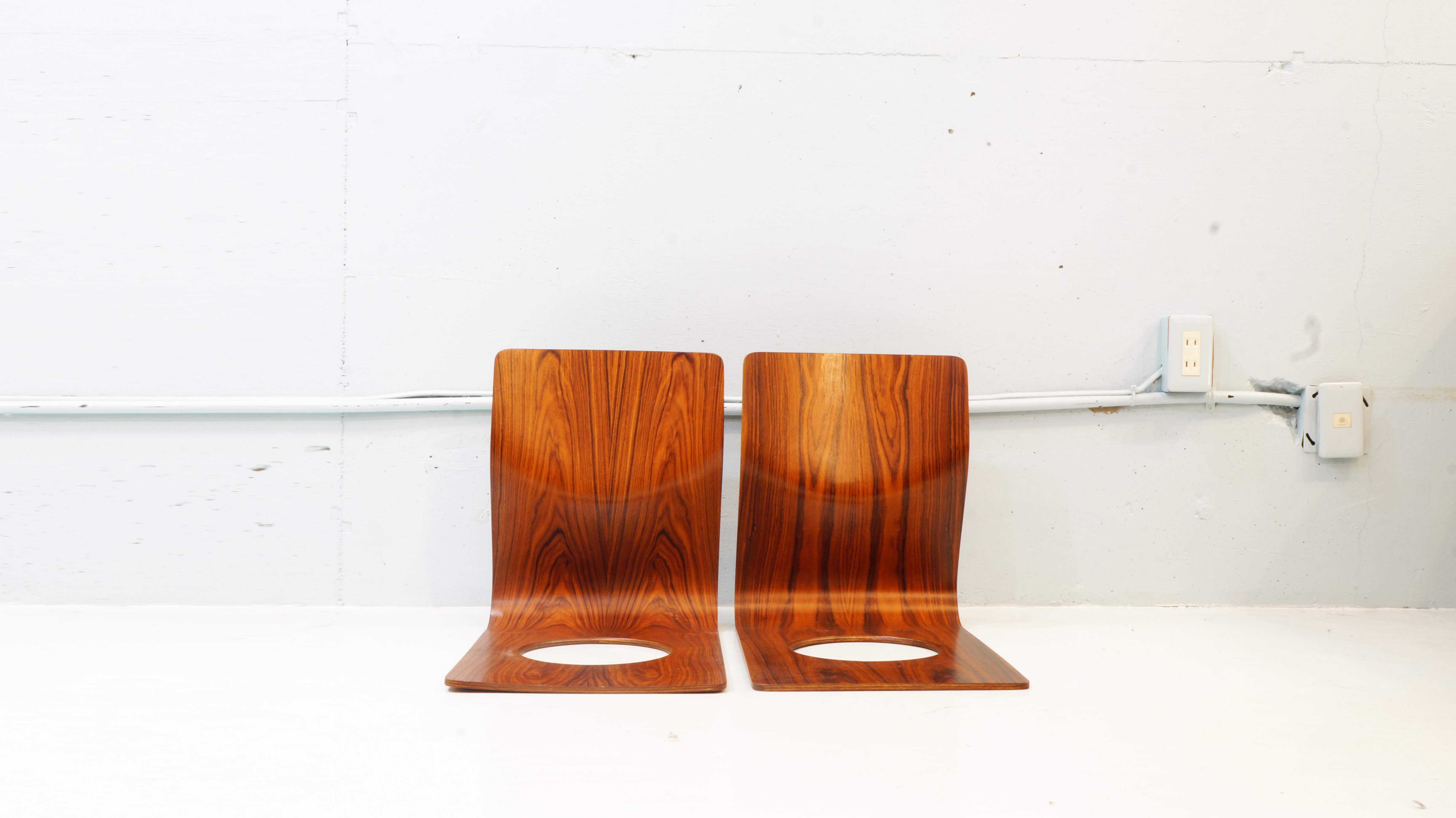 日本でいち早く成形合板を実用化させ数々のロングセラーを生み出してきた日本が誇る家具メーカー　この技術の可能性を認めた才能溢れるデザイナーや建築家たちは数多くいます。その中の一人がこちらの座椅子のデザインを手がけた日本人デザイナー　藤森健次　です。1911年10月1日生まれ　1954～55年、フィンランドの国立ユヴァスキラ美術大学のインダストリアル・デザイン科と室内建築インテリアデザイン科に留学。フィンランドならではの積層材を使用した家具がイルマリ・タピオヴァラによって数多くデザインされ、藤森さんはその影響を受け 帰国後スカンジナビアで学んだ機能的で無駄な要素を排し、素材の持ち味を活かすデザインとして1963年に生れたのが 　座イス　です。こちらの座椅子は、背もたれと座面を成形合板一枚で三次元曲面で加工された極めてシンプルな構造。材の持つ適度な撓りが身体にフィットし圧迫感を和らげた心地良い座り心地を実現、僅か1.7kgと女性でも手軽に扱える重量で末永くご使用頂ける丈夫な造りとなっております。座面に空いた穴は、座布団等を置いた際に畳や絨毯との摩擦を生み出し、ズレを防ぐと共に軽量化と変形防止、且つ持ち運びが容易なフォルムとなっており、積み重ねも可能。また、フィラデルフィア美術館のパーマネントコレクションにも収蔵されております。販売から半世紀も続くロングセラーの商品です。お探しだった方は、是非この機会にいかがでしょうか。～【東京都杉並区阿佐ヶ谷北アンティークショップ 古一/ZACK高円寺店】　古一では出張無料買取も行っております。杉並区周辺はもちろん、世田谷区・目黒区・武蔵野市・新宿区等の東京近郊のお見積もりも！ビンテージ家具・インテリア雑貨・ランプ・USED品・ リサイクルなら古一へ～