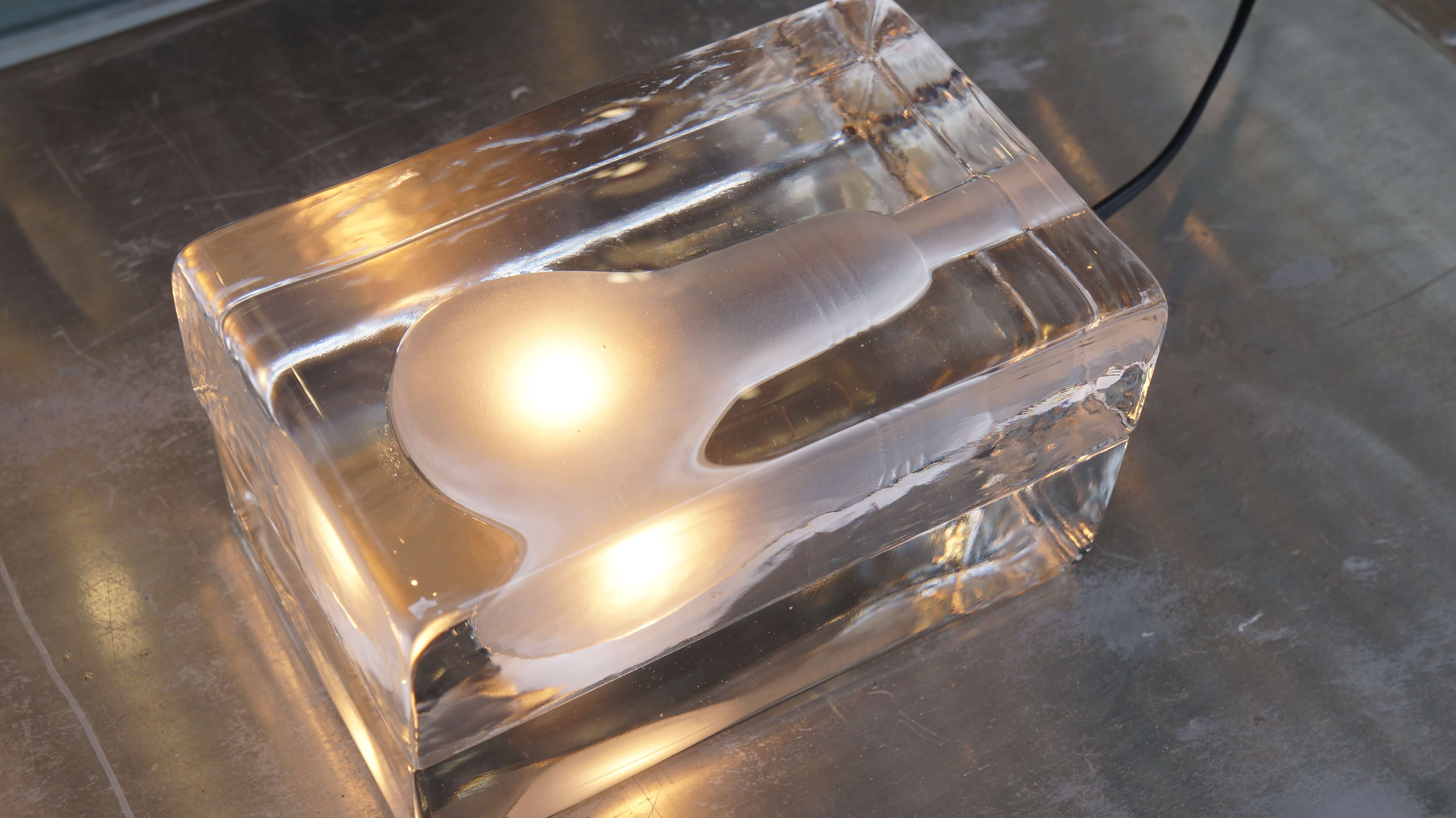 フィンランド出身のデザイナー、ハッリ・コスキネンの名を一躍有名にした、 「氷の中に電球を閉じ込める」という斬新なアイデアから生まれた「ブロックランプ」。 こちらはオリジナルサイズになります。 構造はいたってシンプル。 ガラスの内側が電球の形にくり抜かれ、くり抜かれた部分をフロスト加工で仕上げいます。 この分厚いガラスのブロックは耐久性が高く温度変化にも強い上質なガラスが使われており、 一つ一つ職人の手によって生み出されています。 氷のように冷たそうなガラスのブロックに明かりを灯すと、 あたたかな光が浮かび上がるという不思議なデザイン。 まるで氷の中で電球が凍ってしまい、その氷が今にも解け出しそうです。 幻想的でアート作品のようなこのブロックランプはMoMA(ニューヨーク近代美術館)の パーマネントコレクションにも選ばれています。 15wのとても優しい光なので、明るさは強くありませんが、 床置きできるという利点があるので、ベッドルームのフットライトや リビングの間接照明にもおすすめです。 また、明かりを灯していない時の姿もとても魅力的です。 無造作に置いてもオブジェとして成立する存在感はばっちり。 ブロックランプの幻想的で優しい明かりでお部屋をおしゃれに 演出してみてはいかがでしょうか♪ ～【東京都杉並区阿佐ヶ谷北アンティークショップ 古一/ZACK高円寺店】　古一/ふるいちでは出張無料買取も行っております。杉並区周辺はもちろん、世田谷区・目黒区・武蔵野市・新宿区等の東京近郊のお見積もりも！ビンテージ家具・インテリア雑貨・ランプ・USED品・ リサイクルなら古一/フルイチへ～